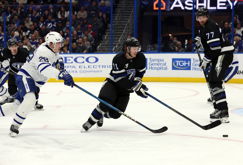 Nov 30, 2024; Tampa, Florida, USA; Tampa Bay Lightning center Brayden Point (21) skates with the puck as Toronto Maple Leafs right wing Pontus Holmberg (29) defends during the second period at Amalie Arena. Mandatory Credit: Kim Klement Neitzel-Imagn Images