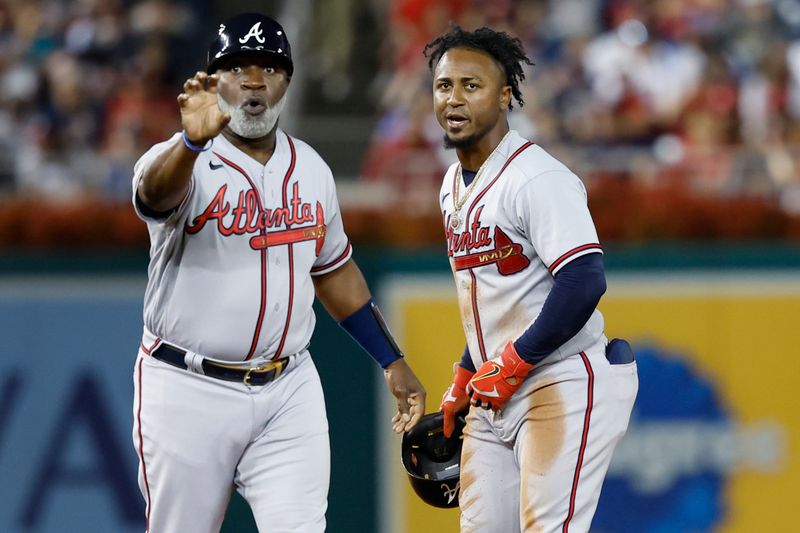 Sep 21, 2023; Washington, District of Columbia, USA; Atlanta Braves first base coach Eric Young Sr. (L) gestures to the Washington Nationals dugout for the baseball hit by Braves second baseman Ozzie Albies (R) after Albies recorded his 100th RBI on the season during the third inning at Nationals Park. Mandatory Credit: Geoff Burke-USA TODAY Sports