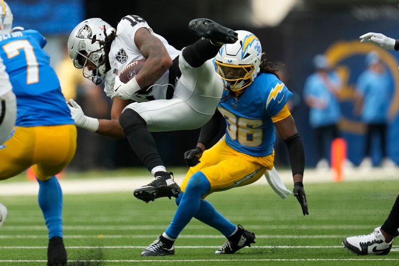 Las Vegas Raiders wide receiver Jakobi Meyers (16) falls forward next to Los Angeles Chargers cornerback Ja'Sir Taylor (36) during the first half of an NFL football game, Sunday, Sept. 8, 2024, in Inglewood, Calif. (AP Photo/Ashley Landis)