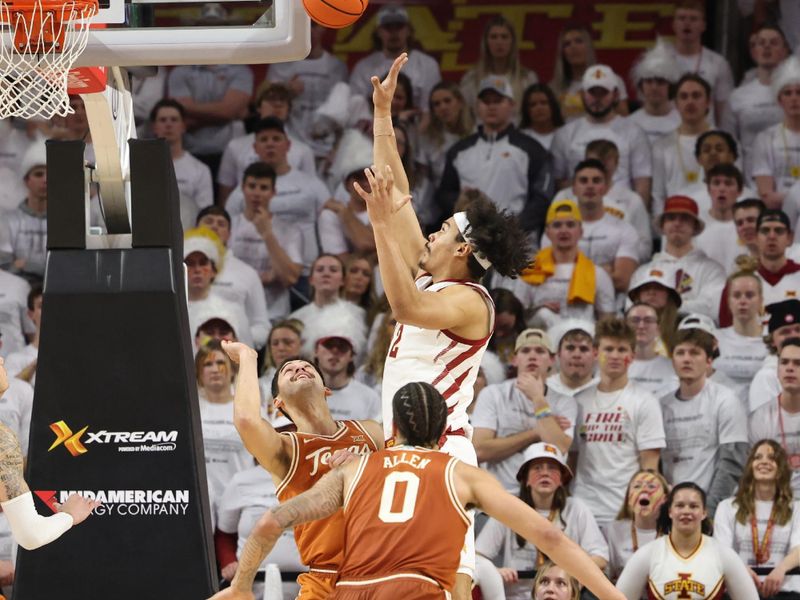 Jan 17, 2023; Ames, Iowa, USA; Iowa State Cyclones forward Robert Jones (12) shoots over Texas Longhorns forward Timmy Allen (0) and forward Brock Cunningham (30) during the second half at James H. Hilton Coliseum. Mandatory Credit: Reese Strickland-USA TODAY Sports