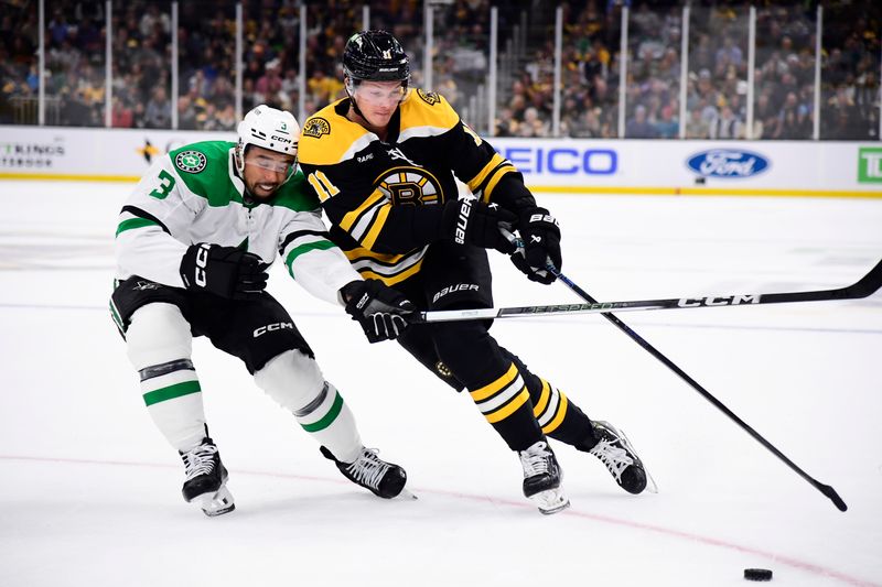 Oct 24, 2024; Boston, Massachusetts, USA;  Boston Bruins center Trent Frederic (11) controls the puck while Dallas Stars defenseman Mathew Dumba (3) defends during the first period at TD Garden. Mandatory Credit: Bob DeChiara-Imagn Images