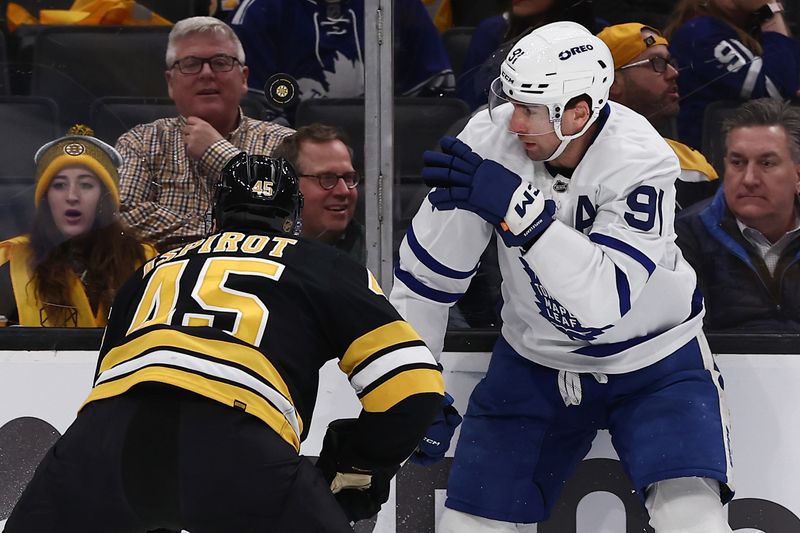 Mar 24, 2026; Boston, Massachusetts, USA; Toronto Maple Leafs center John Tavares (91) eyes a loose puck over the head of Boston Bruins defenseman Jonathan Aspirot (45) during the first period at TD Garden. Mandatory Credit: Winslow Townson-Imagn Images