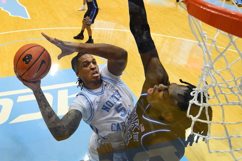 Mar 4, 2023; Chapel Hill, North Carolina, USA; North Carolina Tar Heels forward Armando Bacot (5) shoots as Duke Blue Devils forward Mark Mitchell (25) defends in the second half at Dean E. Smith Center. Mandatory Credit: Bob Donnan-USA TODAY Sports