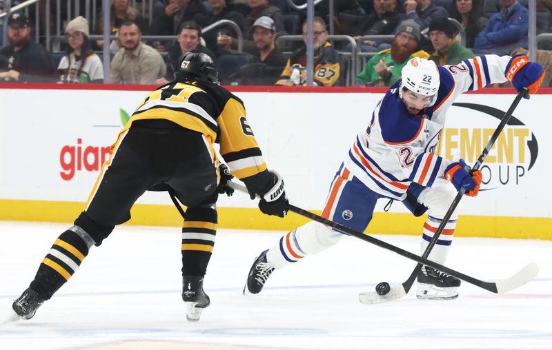 Dec 16, 2025; Pittsburgh, Pennsylvania, USA; Edmonton Oilers center Matt Savoie (22) moves the puck against Pittsburgh Penguins right wing Rickard Rakell (67) during the second period at PPG Paints Arena. Mandatory Credit: Charles LeClaire-Imagn Images