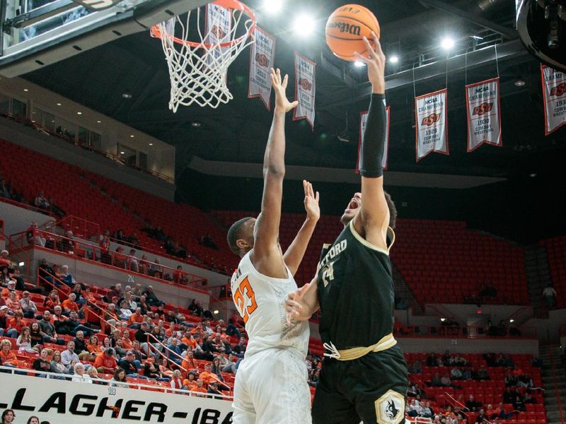 Dec 20, 2023; Stillwater, Oklahoma, USA; Wofford Terriers center Kyler Filewich (14) puts up a shot over Oklahoma State Cowboys center Brandon Garrison (23) during the second half at Gallagher-Iba Arena. Mandatory Credit: William Purnell-USA TODAY Sports