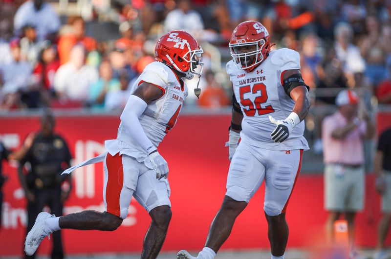 Sep 23, 2023; Houston, Texas, USA; Sam Houston State Bearkats wide receiver Al'vonte Woodard (4) celebrates with offensive lineman D'Ary Patton (52) after a reception during the first quarter against the Houston Cougars at TDECU Stadium. Mandatory Credit: Troy Taormina-USA TODAY Sports