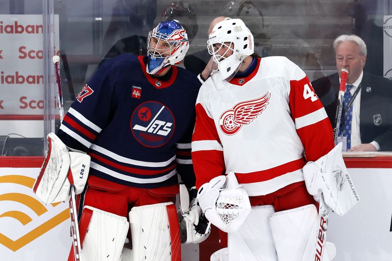 Dec 20, 2023; Winnipeg, Manitoba, CAN; Winnipeg Jets goaltender Connor Hellebuyck (37) and Detroit Red Wings goaltender Michael Hutchinson (45) talk during warm up at Canada Life Centre. Mandatory Credit: James Carey Lauder-USA TODAY Sports