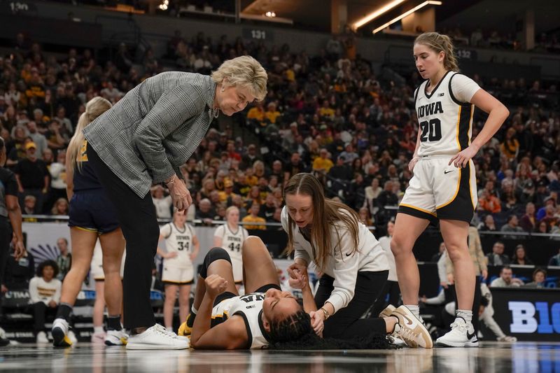 Mar 9, 2024; Minneapolis, MN, USA;  Iowa Hawkeyes head coach Lisa Bluder, a member of the training staff, and guard Kate Martin (20) check on forward Hannah Stuelke (45) after she fell awkwardly on a basket against the Michigan Wolverines during the second half of a Big Ten Women's Basketball tournament semifinal at Target Center. Mandatory Credit: Nick Wosika-USA TODAY Sports