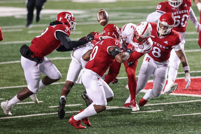 Dec 18, 2020; Piscataway, New Jersey, USA; Nebraska Cornhuskers quarterback Adrian Martinez (2) fumbles the ball as Rutgers Scarlet Knights defensive back Christian Izien (0) defends during the first half at SHI Stadium. Mandatory Credit: Vincent Carchietta-USA TODAY Sports