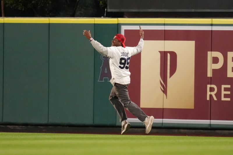 May 28, 2025; Anaheim, California, USA; A fan runs onto the field during the game between the New York Yankees and the Los Angeles Angels at Angel Stadium. Mandatory Credit: Kirby Lee-Imagn Images