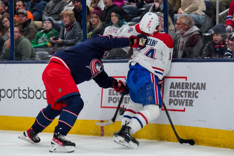 Nov 29, 2023; Columbus, Ohio, USA;  Columbus Blue Jackets defenseman Ivan Provorov (9) checks Montreal Canadiens center Nick Suzuki (14) along the boards in the first period at Nationwide Arena. Mandatory Credit: Aaron Doster-USA TODAY Sports