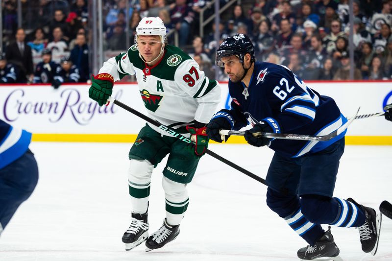 Feb 20, 2024; Winnipeg, Manitoba, CAN; Winnipeg Jets forward Nino Niederreiter (62) and Minnesota Wild forward Kirill Kaprizov (97) look for the puck during first period at Canada Life Centre. Mandatory Credit: Terrence Lee-USA TODAY Sports