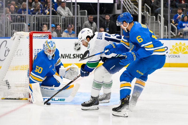 Oct 30, 2025; St. Louis, Missouri, USA; St. Louis Blues goaltender Jordan Binnington (50) and defenseman Philip Broberg (6) defend the net against Vancouver Canucks left wing Arshdeep Bains (13) during the first period at Enterprise Center. Mandatory Credit: Jeff Curry-Imagn Images