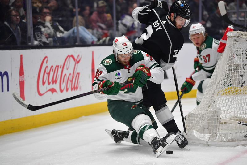 Mar 20, 2024; Los Angeles, California, USA; Los Angeles Kings defenseman Matt Roy (3) plays for the puck against Minnesota Wild right wing Ryan Hartman (38) during the first period at Crypto.com Arena. Mandatory Credit: Gary A. Vasquez-USA TODAY Sports