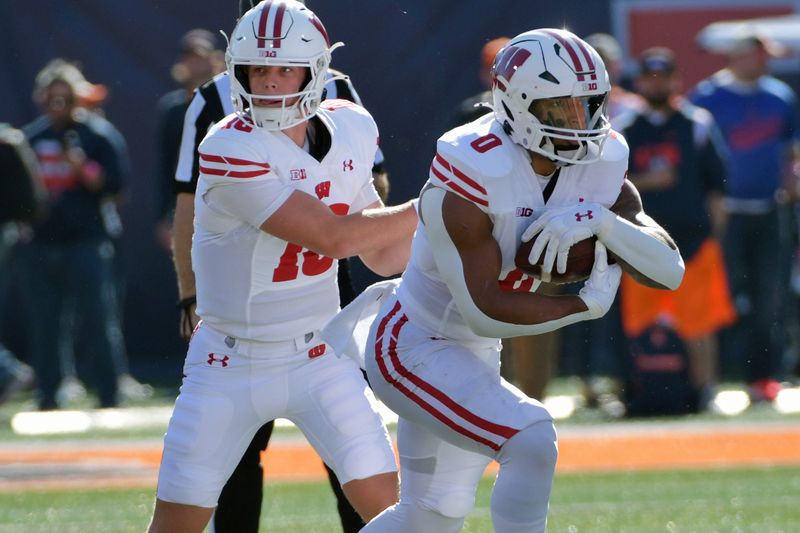 Oct 21, 2023; Champaign, Illinois, USA;  Wisconsin Badgers quarterback Braedyn Locke (18) hands the ball to running back Braelon Allen (0) against the Illinois Fighting Illini during the first half at Memorial Stadium. Mandatory Credit: Ron Johnson-USA TODAY Sports