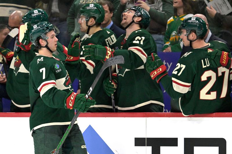 Jan 25, 2024; Saint Paul, Minnesota, USA; Minnesota Wild defenseman Brock Faber (7) celebrates his assist on a power play goal by forward Matt Boldy (12) with forward Brandon Duhaime (21) and forward Jacob Lucchini (27) during the third period at Xcel Energy Center. Mandatory Credit: Nick Wosika-USA TODAY Sports