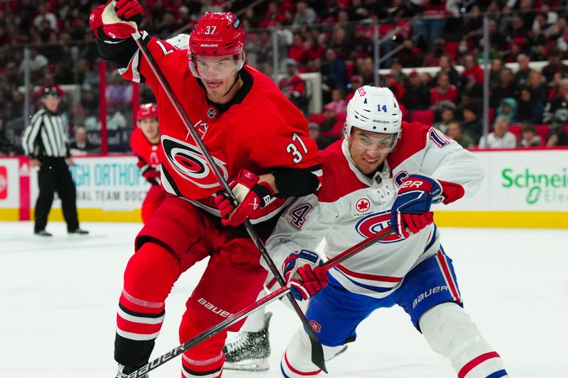 Dec 28, 2023; Raleigh, North Carolina, USA; Carolina Hurricanes right wing Andrei Svechnikov (37) and Montreal Canadiens center Nick Suzuki (14) battle for position during the first period at PNC Arena. Mandatory Credit: James Guillory-USA TODAY Sports