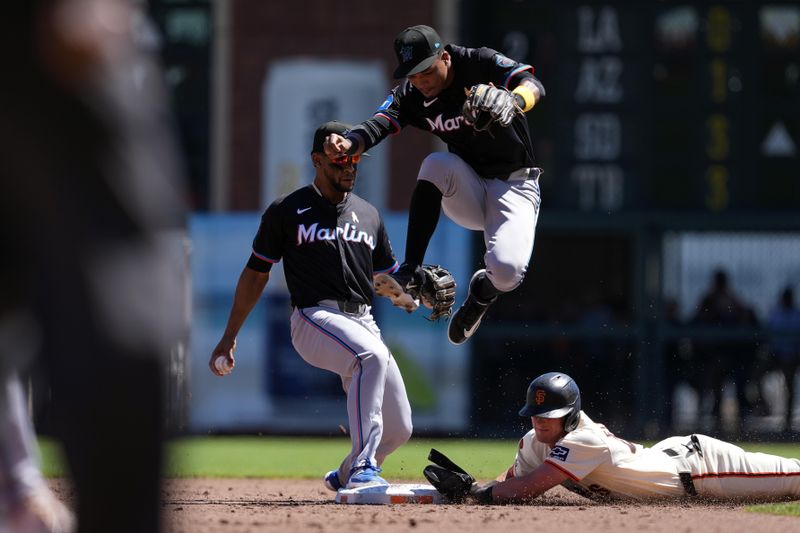 Sep 1, 2024; San Francisco, California, USA; Miami Marlins shortatop Otto Lopez (left) steps on second base to force out San Francisco Giants shortstop Tyler Fitzgerald (sliding) as Miami Marlins second baseman Jose Devers (center right) leaps during the third inning at Oracle Park. Mandatory Credit: Darren Yamashita-USA TODAY Sports