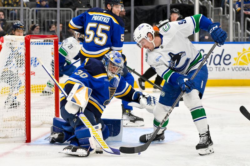 Jan 27, 2025; St. Louis, Missouri, USA;  St. Louis Blues goaltender Joel Hofer (30) defends the net against Vancouver Canucks center Linus Karlsson (94) during the third period at Enterprise Center. Mandatory Credit: Jeff Curry-Imagn Images