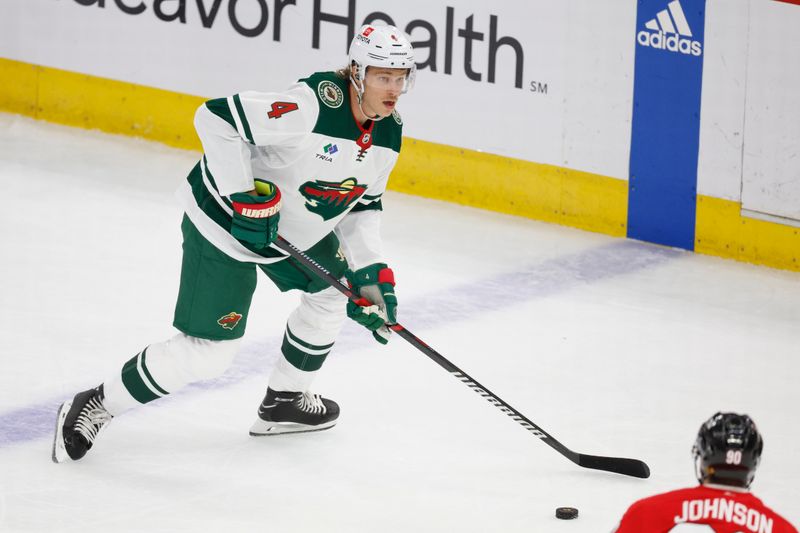 Feb 7, 2024; Chicago, Illinois, USA; Minnesota Wild defenseman Jon Merrill (4) looks to pass the puck against the Chicago Blackhawks during the first period at United Center. Mandatory Credit: Kamil Krzaczynski-USA TODAY Sports