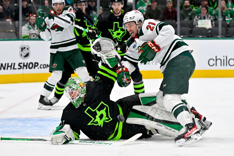 Jan 10, 2024; Dallas, Texas, USA; Minnesota Wild right wing Brandon Duhaime (21) is hit by a Wild slap shot as he attempts a shot on Dallas Stars goaltender Scott Wedgewood (41) during the first period at the American Airlines Center. Mandatory Credit: Jerome Miron-USA TODAY Sports