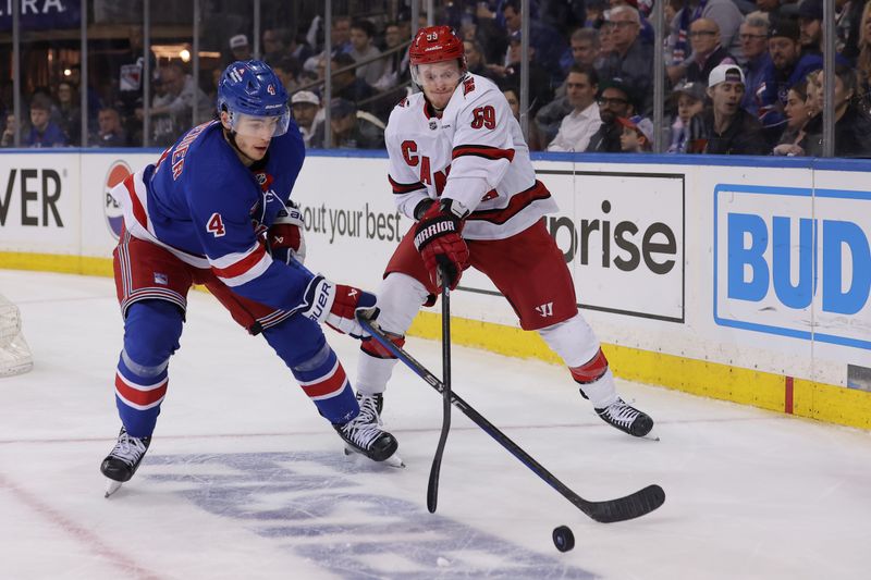 May 13, 2024; New York, New York, USA; New York Rangers defenseman Braden Schneider (4) fights for the puck against Carolina Hurricanes left wing Jake Guentzel (59) during the third period of game five of the second round of the 2024 Stanley Cup Playoffs at Madison Square Garden. Mandatory Credit: Brad Penner-USA TODAY Sports