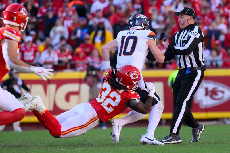 Kansas City Chiefs linebacker Nick Bolton (32) sacks Denver Broncos quarterback Bo Nix (10) as Nix nearly runs into field judge Nate Jones (42) during the second half of an NFL football game, Sunday, Nov. 10, 2024 in Kansas City, Mo. The Chiefs defeated the Broncos, 16-14. (AP Photo/Reed Hoffmann)