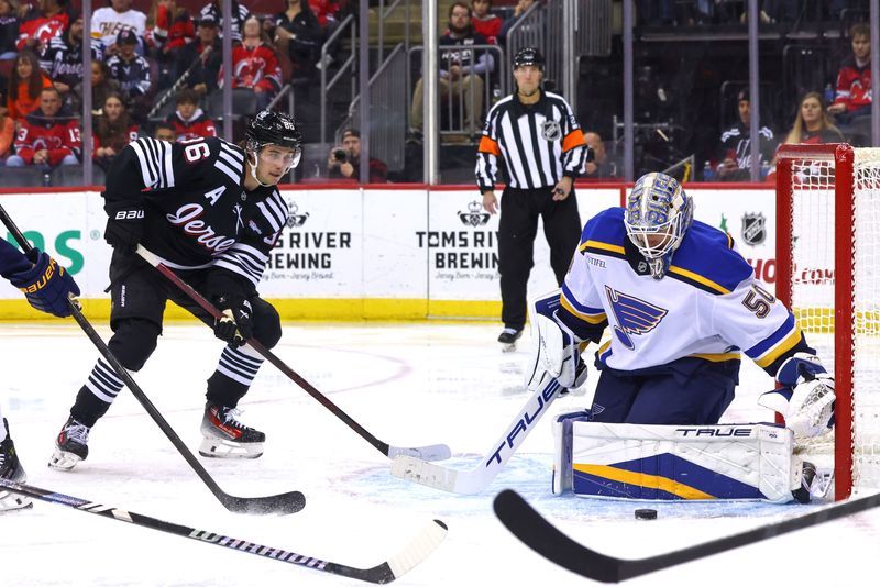 Nov 27, 2024; Newark, New Jersey, USA; St. Louis Blues goaltender Jordan Binnington (50) makes a save while New Jersey Devils center Jack Hughes (86) looks for the rebound during the second period at Prudential Center. Mandatory Credit: Ed Mulholland-Imagn Images