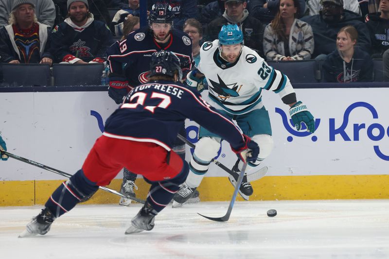 Jan 16, 2025; Columbus, Ohio, USA;  San Jose Sharks right wing Barclay Goodrow (23) chases the puck as Columbus Blue Jackets center Zachary Aston-Reese (27) and center Adam Fantilli (19) defend during the first period at Nationwide Arena. Mandatory Credit: Joseph Maiorana-Imagn Images