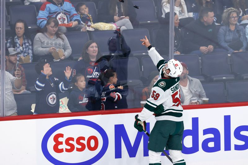 Sep 21, 2024; Winnipeg, Manitoba, CAN; Minnesota Wild Ryan Sandelin tosses a puck to a fan before a preseason game against the Winnipeg Jets at Canada Life Centre. Mandatory Credit: James Carey Lauder-Imagn Images