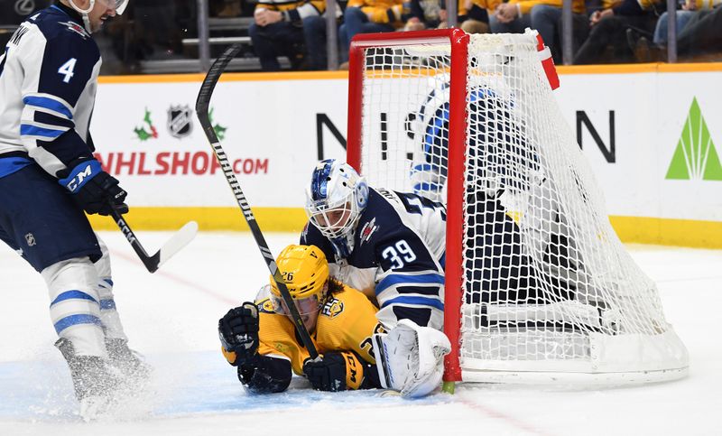 Nov 26, 2023; Nashville, Tennessee, USA; Winnipeg Jets goaltender Laurent Brossoit (39) is hit by Nashville Predators center Philip Tomasino (26) after a save during the third period at Bridgestone Arena. Mandatory Credit: Christopher Hanewinckel-USA TODAY Sports