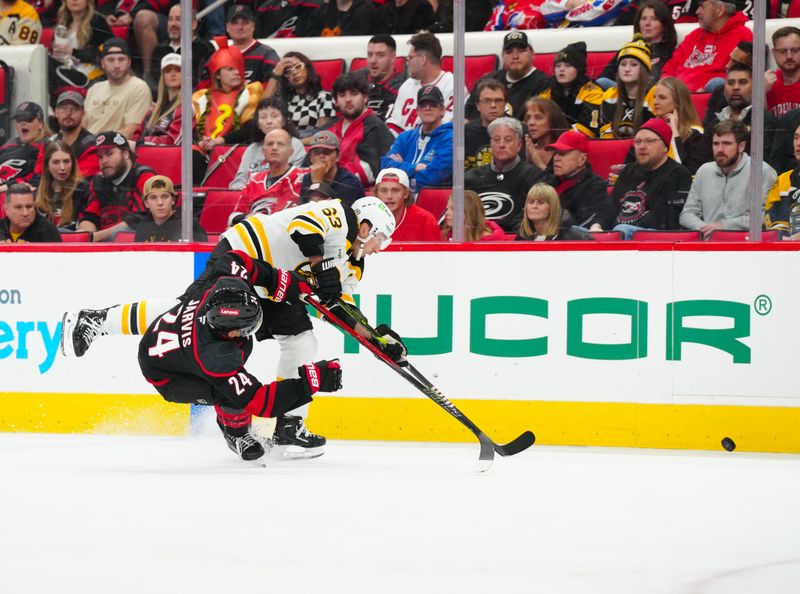 Oct 31, 2024; Raleigh, North Carolina, USA;  Boston Bruins left wing Brad Marchand (63) and Carolina Hurricanes center Seth Jarvis (24) battle over the puck during the second period at Lenovo Center. Mandatory Credit: James Guillory-Imagn Images