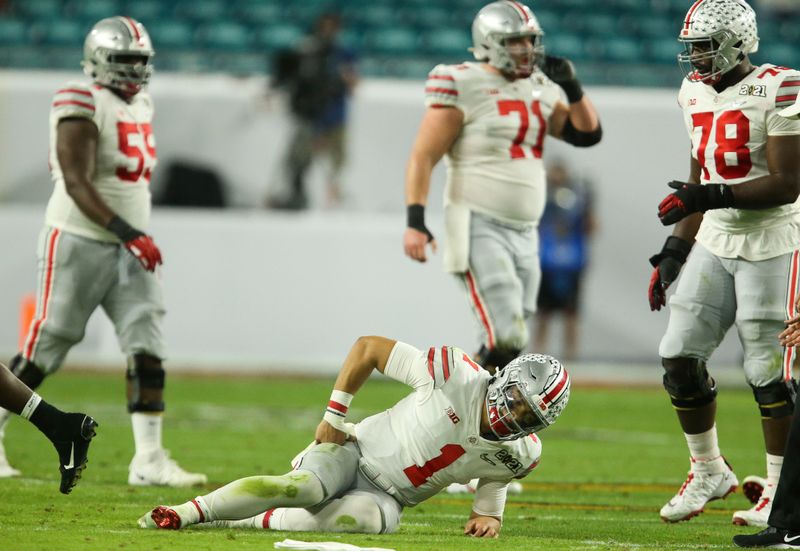 Jan 11, 2021; Miami Gardens, Florida, USA;  Ohio State quarterback Justin Fields (1) is slow to get up after being hit by Alabama defenders in the College Football Playoff National Championship Game in Hard Rock Stadium. Mandatory Credit: Gary Cosby-USA TODAY Sports