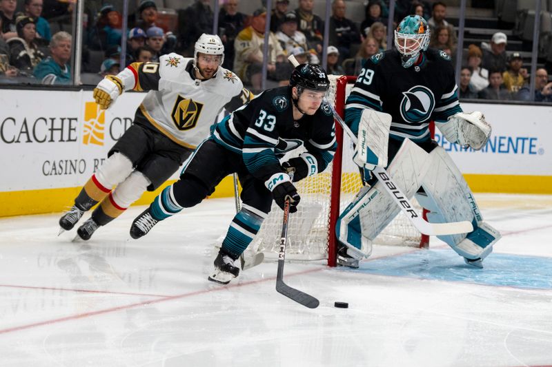 Feb 19, 2024; San Jose, California, USA; San Jose Sharks defenseman Calen Addison (33) controls the puck behind the net against Vegas Golden Knights center Nicolas Roy (10) during the first period at SAP Center at San Jose. Mandatory Credit: Neville E. Guard-USA TODAY Sports