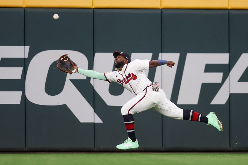 May 12, 2025; Atlanta, Georgia, USA; Atlanta Braves center fielder Michael Harris II (23) reaches for a ball against the Washington Nationals in the eighth inning at Truist Park. Mandatory Credit: Brett Davis-Imagn Images
