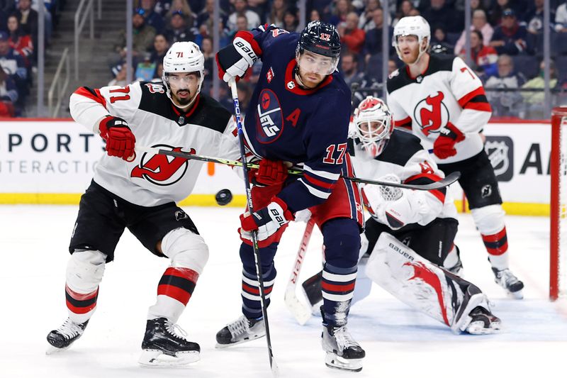 Apr 2, 2023; Winnipeg, Manitoba, CAN; New Jersey Devils defenseman Jonas Siegenthaler (71) and Winnipeg Jets center Adam Lowry (17) watch a flying puck in the second period at Canada Life Centre. Mandatory Credit: James Carey Lauder-USA TODAY Sports