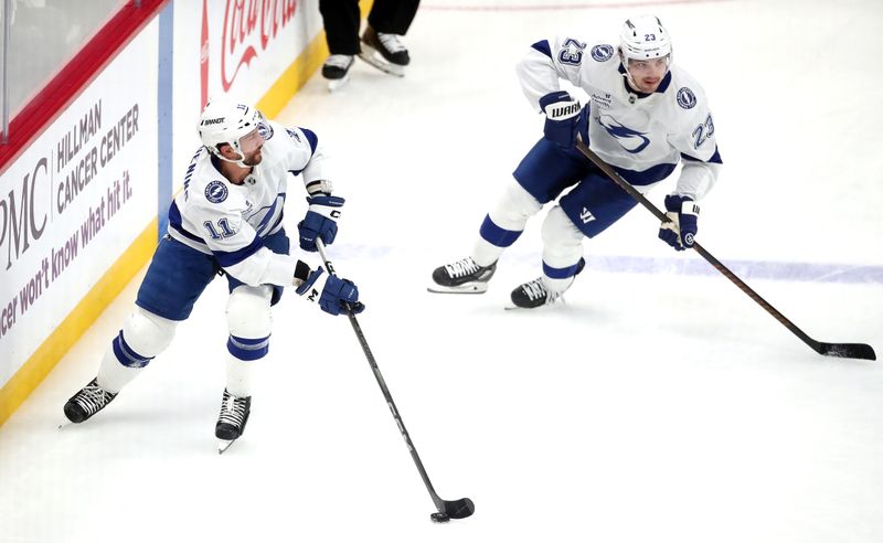 Nov 19, 2024; Pittsburgh, Pennsylvania, USA;  Tampa Bay Lightning center Luke Glendening (11) moves the puck alongside center Michael Eyssimont (23) against the Pittsburgh Penguins during the second period at PPG Paints Arena. Mandatory Credit: Charles LeClaire-Imagn Images