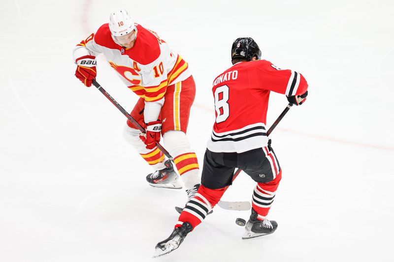 Jan 13, 2025; Chicago, Illinois, USA; Calgary Flames center Jonathan Huberdeau (10) battles for the puck with Chicago Blackhawks center Ryan Donato (8) during the second period at United Center. Mandatory Credit: Kamil Krzaczynski-Imagn Images