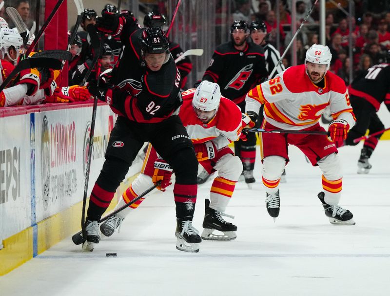 Mar 10, 2024; Raleigh, North Carolina, USA;  Carolina Hurricanes center Evgeny Kuznetsov (92) tries to control the puck against Calgary Flames right wing Matt Coronato (27) at PNC Arena. Mandatory Credit: James Guillory-USA TODAY Sports