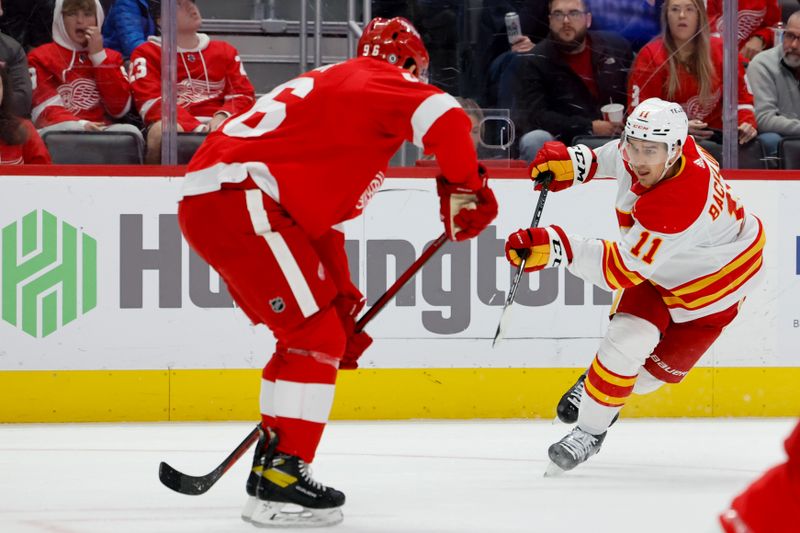 Oct 22, 2023; Detroit, Michigan, USA;  Calgary Flames center Mikael Backlund (11) takes a shot defended by Detroit Red Wings defenseman Jake Walman (96) in the first period at Little Caesars Arena. Mandatory Credit: Rick Osentoski-USA TODAY Sports