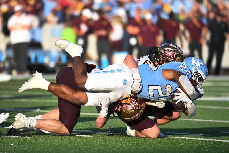 Sep 16, 2023; Chapel Hill, North Carolina, USA;  North Carolina Tar Heels running back British Brooks (24) is tackled by Minnesota Golden Gophers defensive back Jack Henderson (20) and linebacker Maverick Baranowski (6) in the fourth quarter at Kenan Memorial Stadium. Mandatory Credit: Bob Donnan-USA TODAY Sports