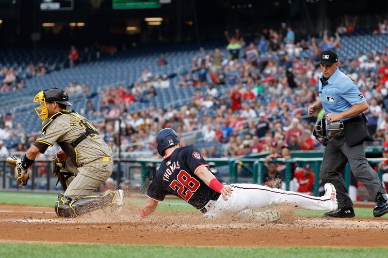 Jul 24, 2024; Washington, District of Columbia, USA; Washington Nationals outfielder Lane Thomas (28) scores a run ahead of a tag by San Diego Padres catcher Kyle Higashioka (20) on an RBI single by Nationals outfielder Jesse Winker (6) during the first inning at Nationals Park. Mandatory Credit: Geoff Burke-USA TODAY Sports