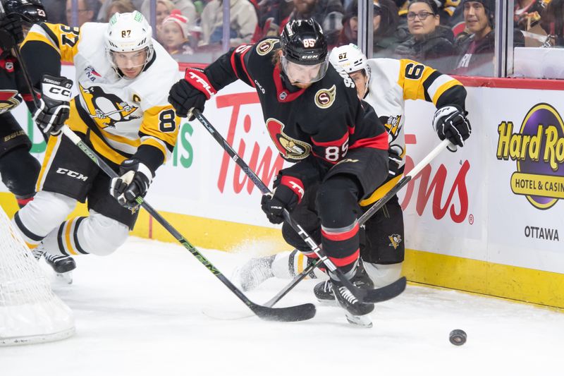 Dec 14, 2024; Ottawa, Ontario, CAN; Ottawa Senators defenseman Jake Sanderson (85) chases the puck with Pittsburgh Penguins center Sidney Crosby (87) and right wing Rickard Rakell (67) in pursuit during the second period at the Canadian Tire Centre. Mandatory Credit: Marc DesRosiers-Imagn Images