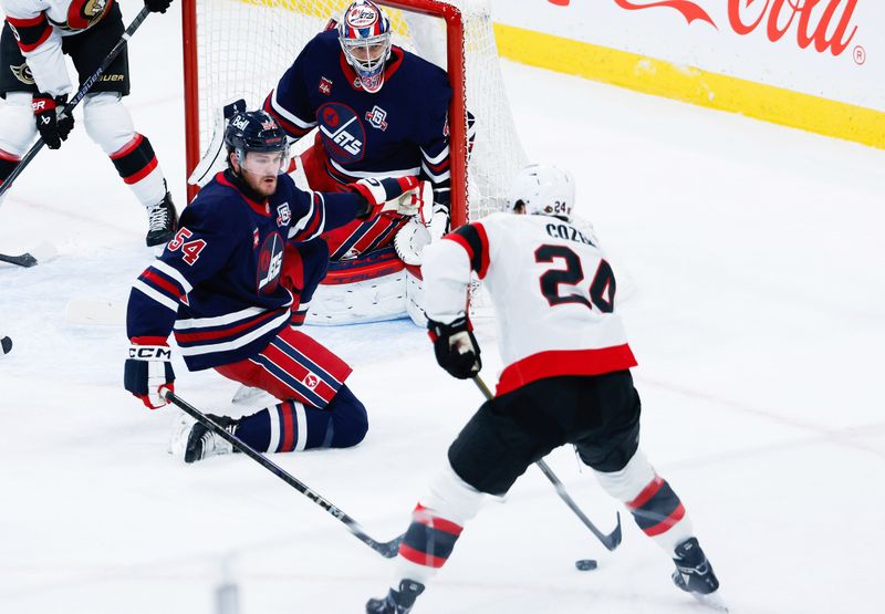 Dec 15, 2025; Winnipeg, Manitoba, CAN;  Winnipeg Jets defenseman Dylan Samberg (54) and goalie Connor Hellebuyck (37) watch Ottawa Senators forward Dylan Cozens (24) during the first period at Canada Life Centre. Mandatory Credit: Terrence Lee-Imagn Images