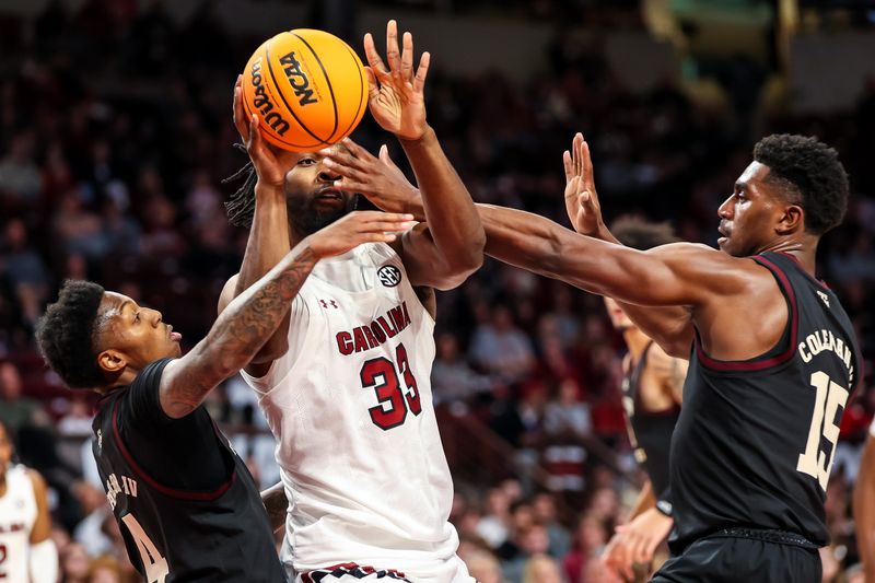 Jan 14, 2023; Columbia, South Carolina, USA; South Carolina Gamecocks forward Josh Gray (33) attempts to pass around Texas A&M Aggies guard Wade Taylor IV (4) and forward Henry Coleman III (15) in the first half at Colonial Life Arena. Mandatory Credit: Jeff Blake-USA TODAY Sports