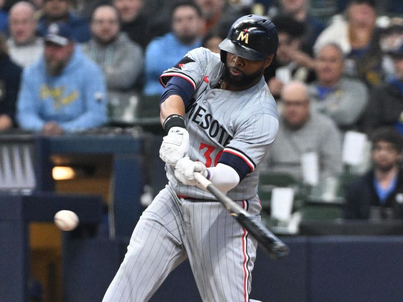 Apr 3, 2024; Milwaukee, Wisconsin, USA; Minnesota Twins first baseman Carlos Santana (30) gets a base hit against the Milwaukee Brewers in the fifth inning at American Family Field. Mandatory Credit: Michael McLoone-USA TODAY Sports