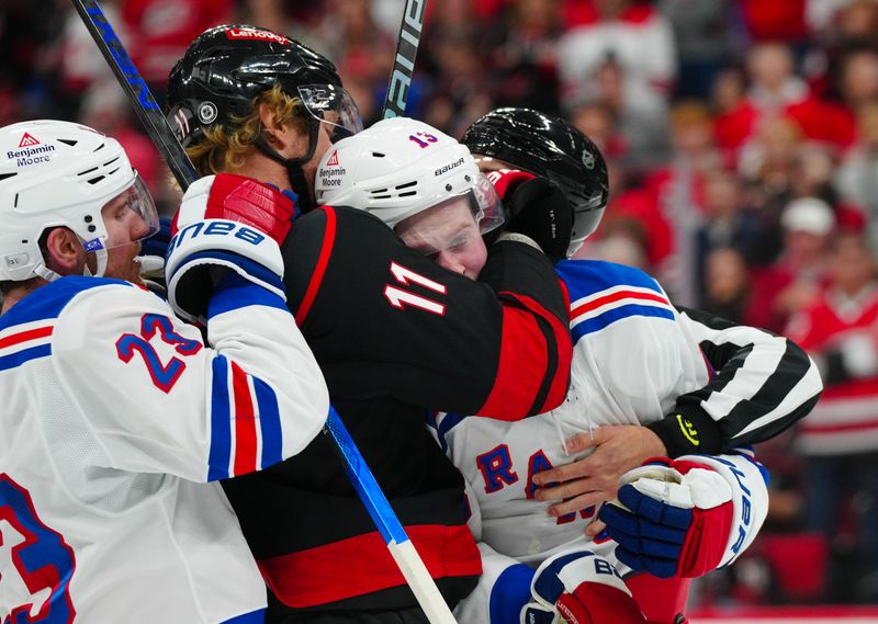 Nov 27, 2024; Raleigh, North Carolina, USA;  Carolina Hurricanes center Jordan Staal (11) grabs New York Rangers left wing Alexis Lafrenière (13) during the third period at Lenovo Center. Mandatory Credit: James Guillory-Imagn Images