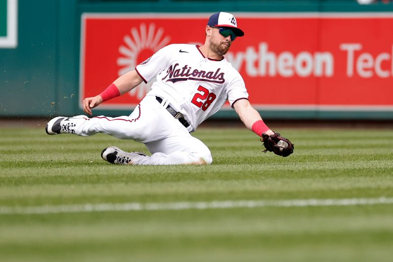 Apr 16, 2023; Washington, District of Columbia, USA; Washington Nationals right fielder Lane Thomas (28) slides to make a catch on a fly ball hit by Cleveland Guardians catcher Mike Zunino (not pictured) during the ninth inning at Nationals Park. Mandatory Credit: Geoff Burke-USA TODAY Sports