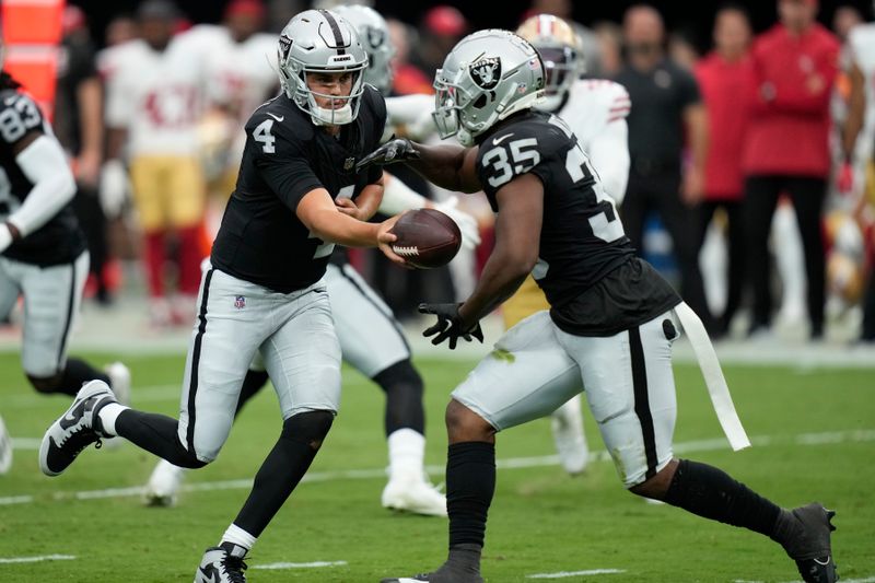 Las Vegas Raiders quarterback Aidan O'Connell (4) hands off to running back Zamir White (35) during the first half of an NFL preseason football game against the San Francisco 49ers, Sunday, Aug. 13, 2023, in Las Vegas. (AP Photo/John Locher)