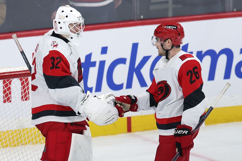 Nov 21, 2025; Winnipeg, Manitoba, CAN; Carolina Hurricanes goaltender Brandon Bussi (32) and defenseman Sean Walker (26) celebrate their victory over then Winnipeg Jets at Canada Life Centre. Mandatory Credit: James Carey Lauder-Imagn Images
